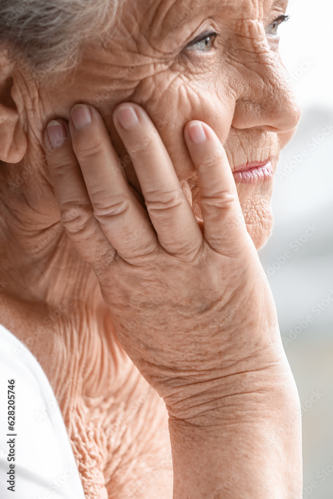 Senior woman looking in window at home, closeup