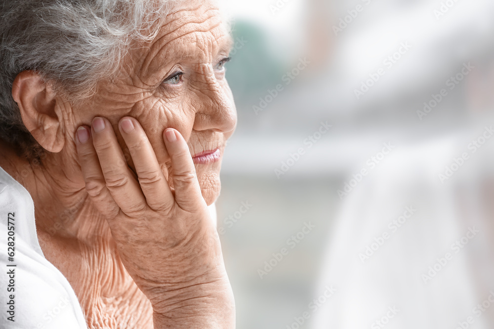 Senior woman looking in window at home, closeup