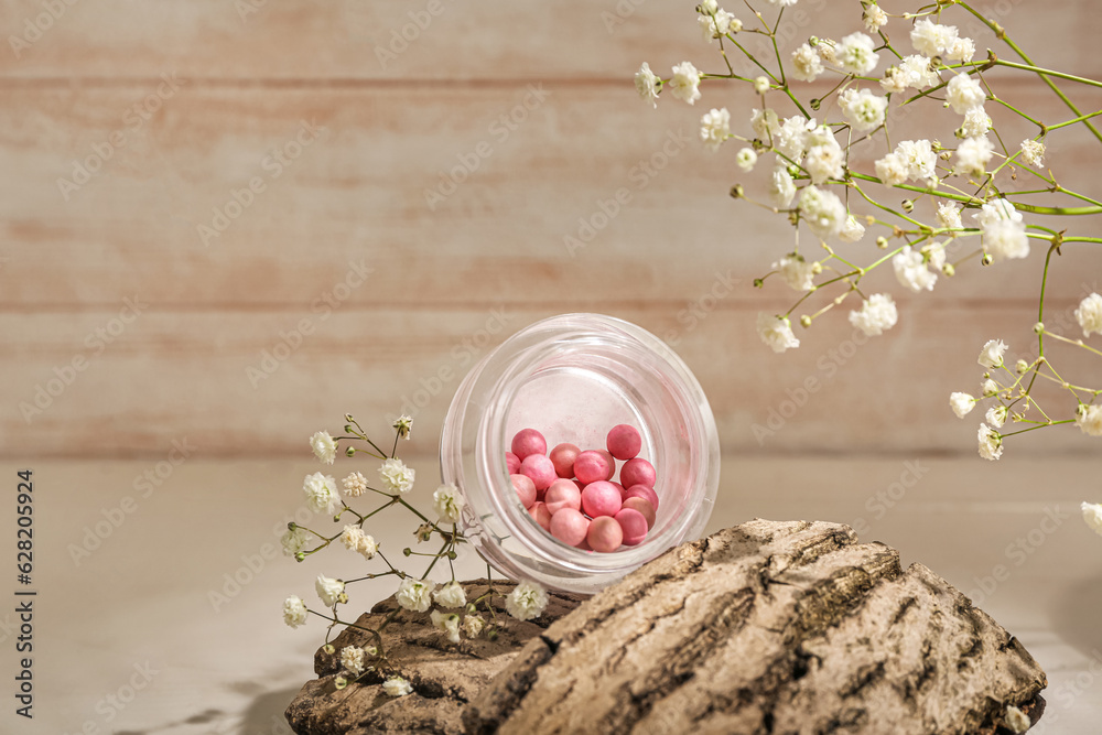 Jar of blush balls, tree bark and gypsophila flowers on light wooden table, closeup