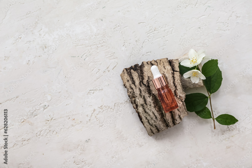 Bottle of cosmetic oil with jasmine flowers and tree bark on white background