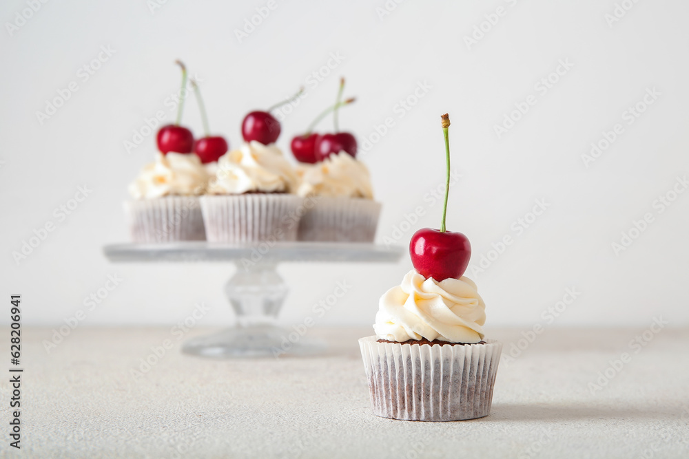 Tasty cherry cupcake on light background