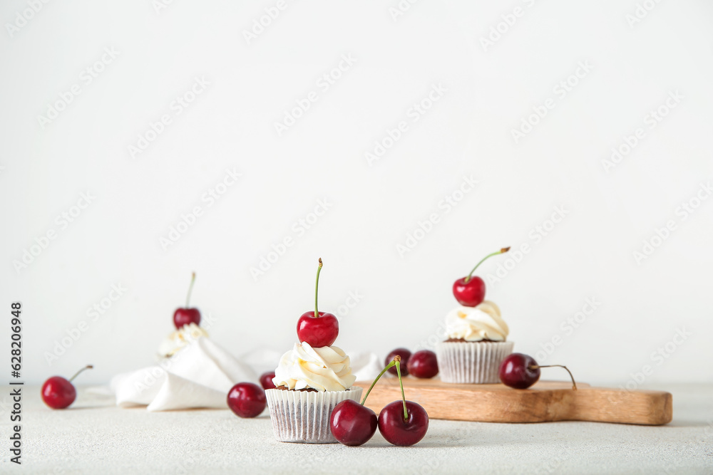 Tasty cherry cupcake on light background