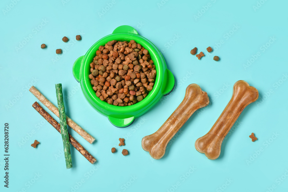 Composition with dog treats and dry food on color background