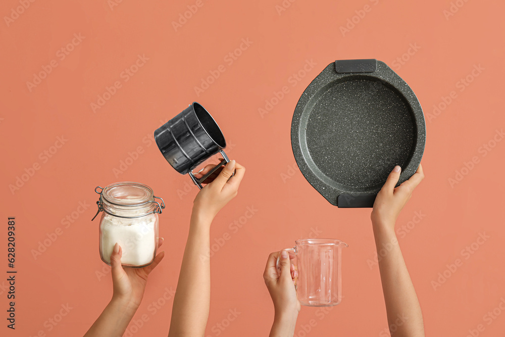 Female hands with baking utensils on pink background