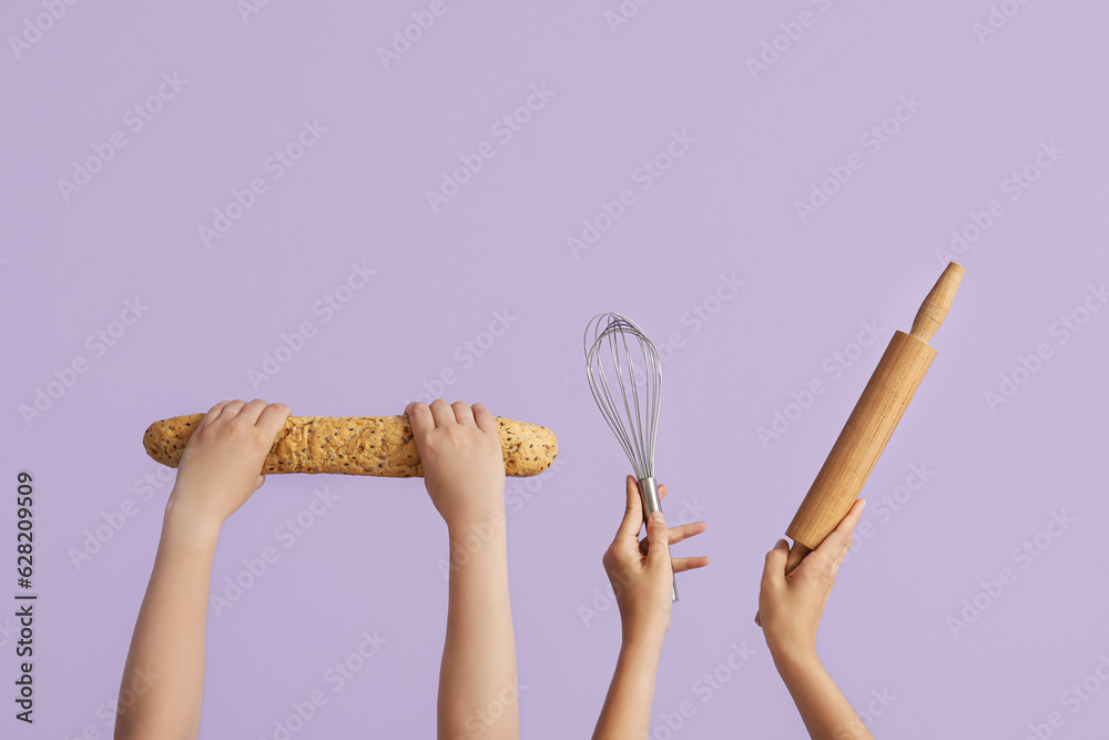 Female hands with baguette, whisk and rolling pin on lilac background