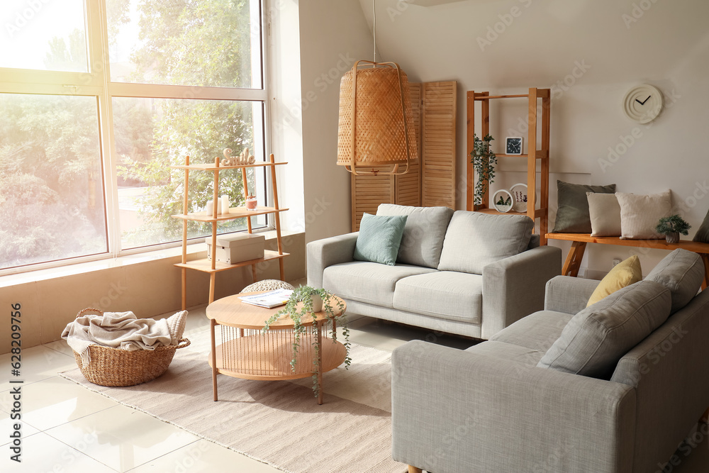 Interior of light living room with cozy grey sofas and wooden coffee table