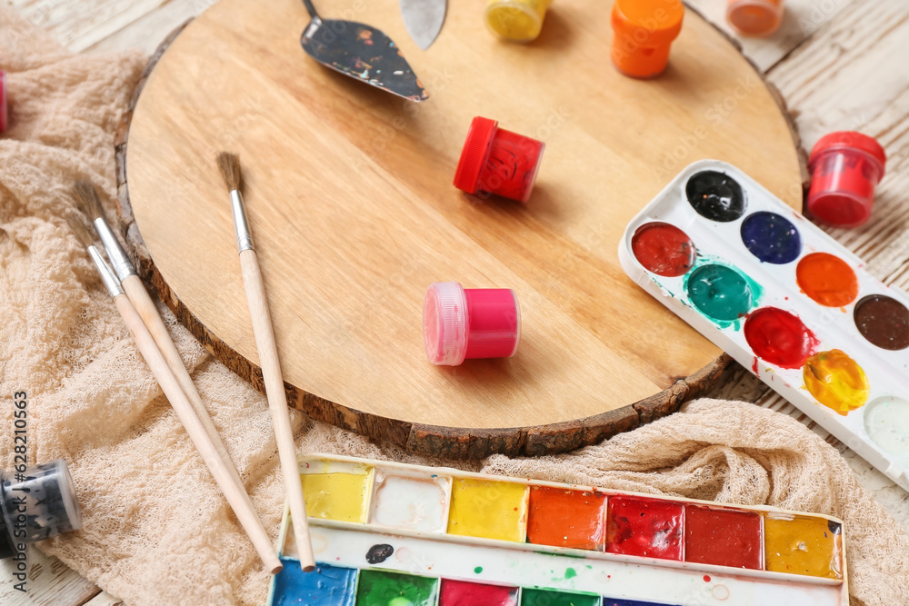 Palette, paints and brushes on white wooden table