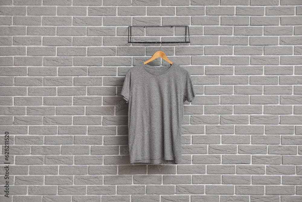 Stylish t-shirt hanging on grey brick wall