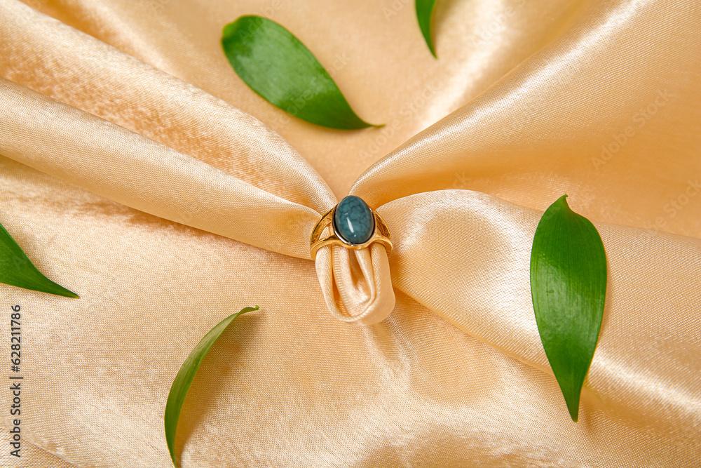 Beautiful ring with plant leaves on beige silk cloth