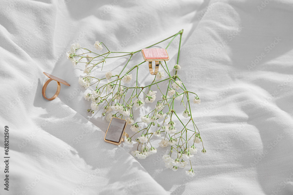 Beautiful elegant rings with gypsophila flowers on white cloth