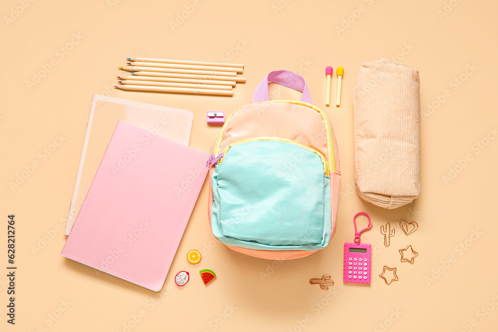 Stylish school backpack with different stationery on orange background