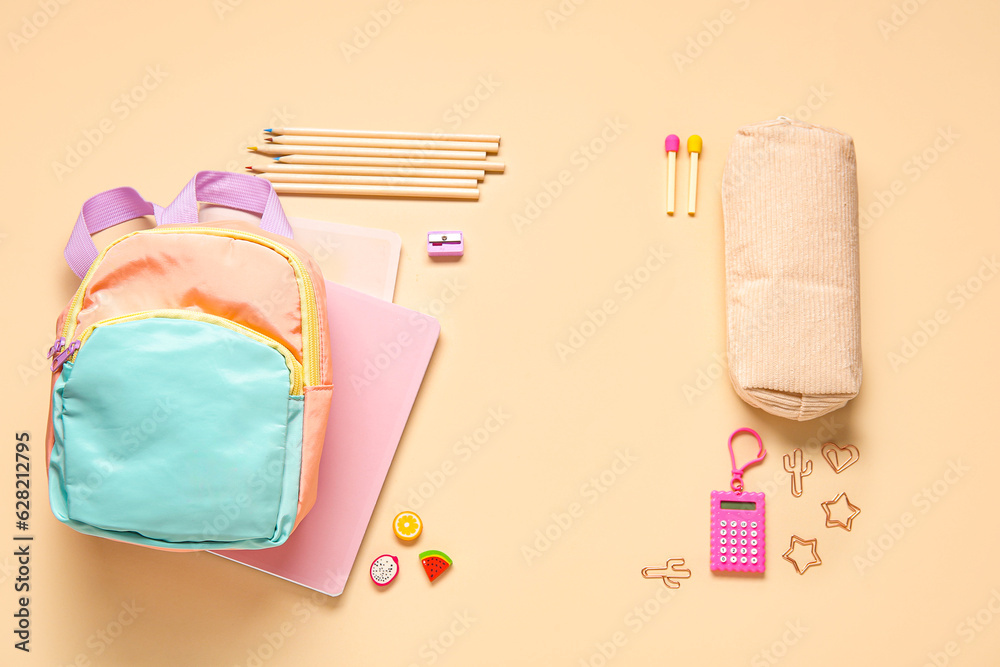 Stylish school backpack with different stationery on orange background