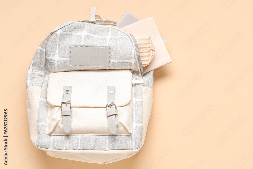 Grey school backpack with different stationery on orange background