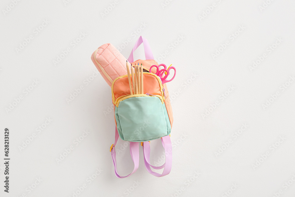 Color school backpack with stationery on light background