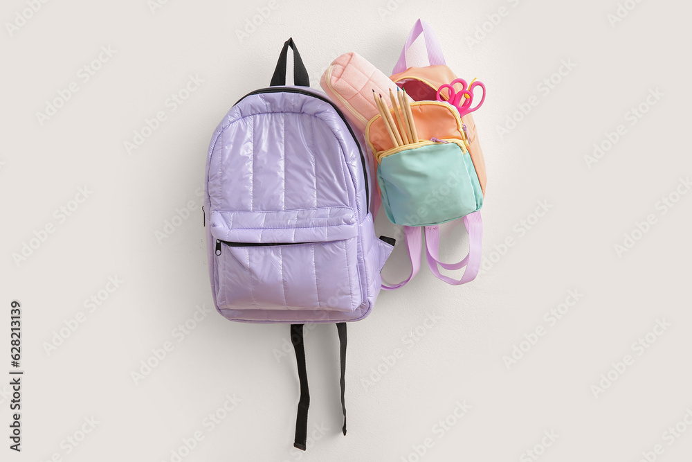 Color school backpacks with stationery on light background