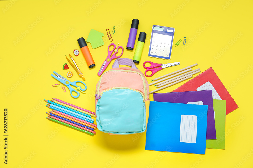 Color school backpack with different stationery on yellow background