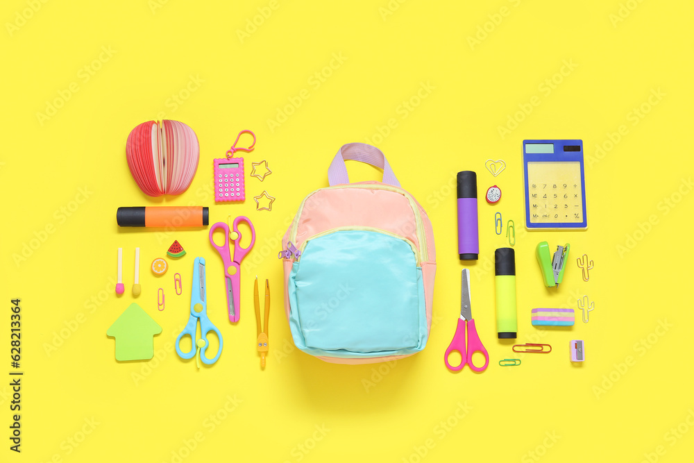 Color school backpack with different stationery on yellow background