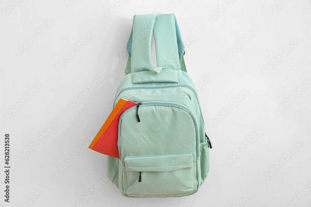 Green school backpack with stationery on white background