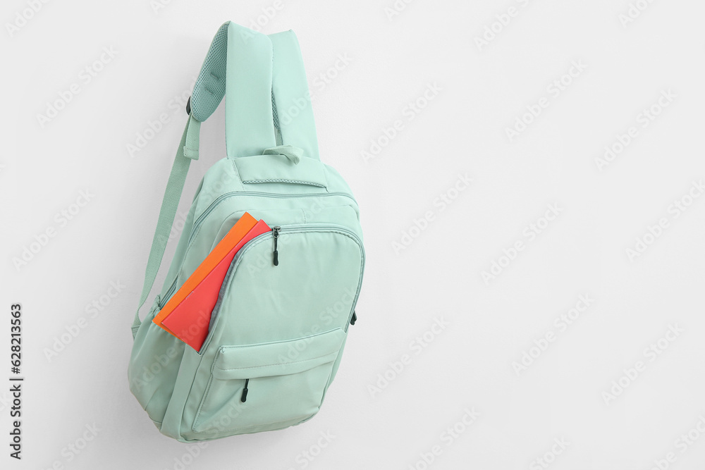 Green school backpack with stationery on white background