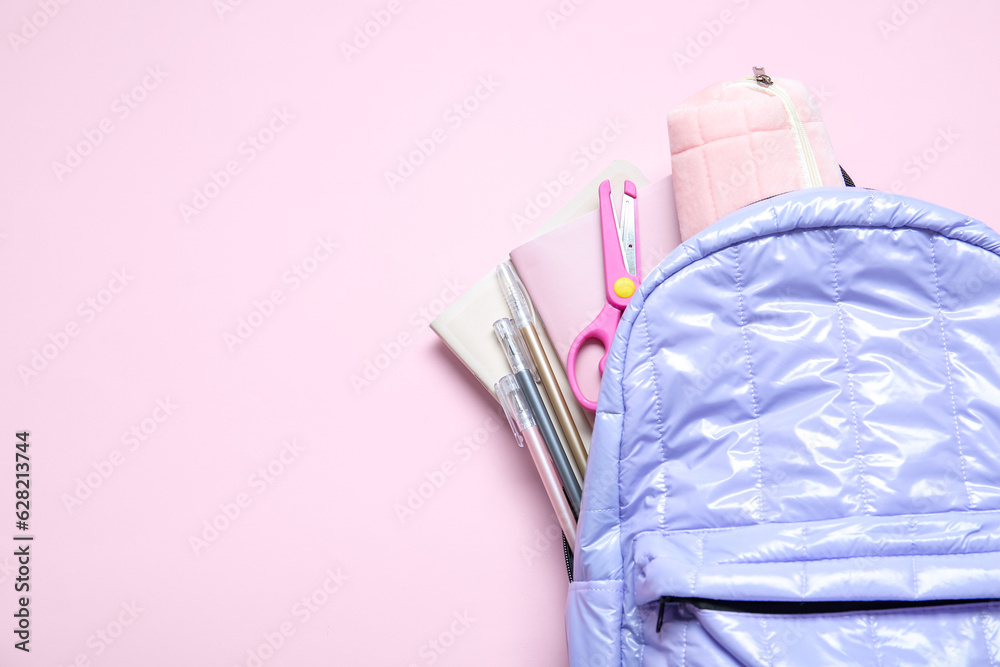 Lilac school backpack with stationery on pink background