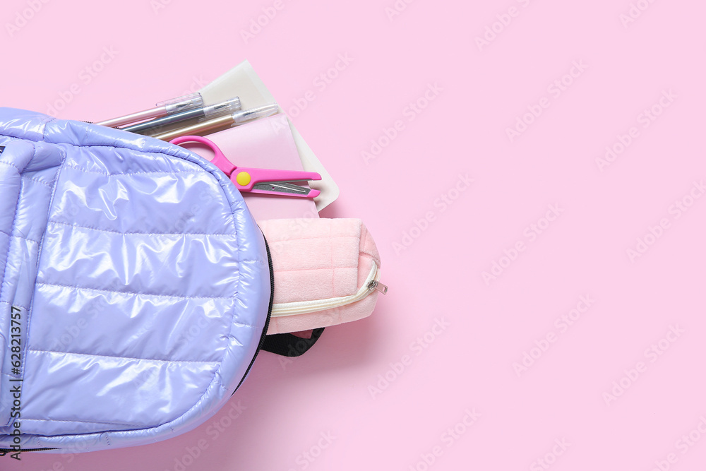 Lilac school backpack with stationery on pink background