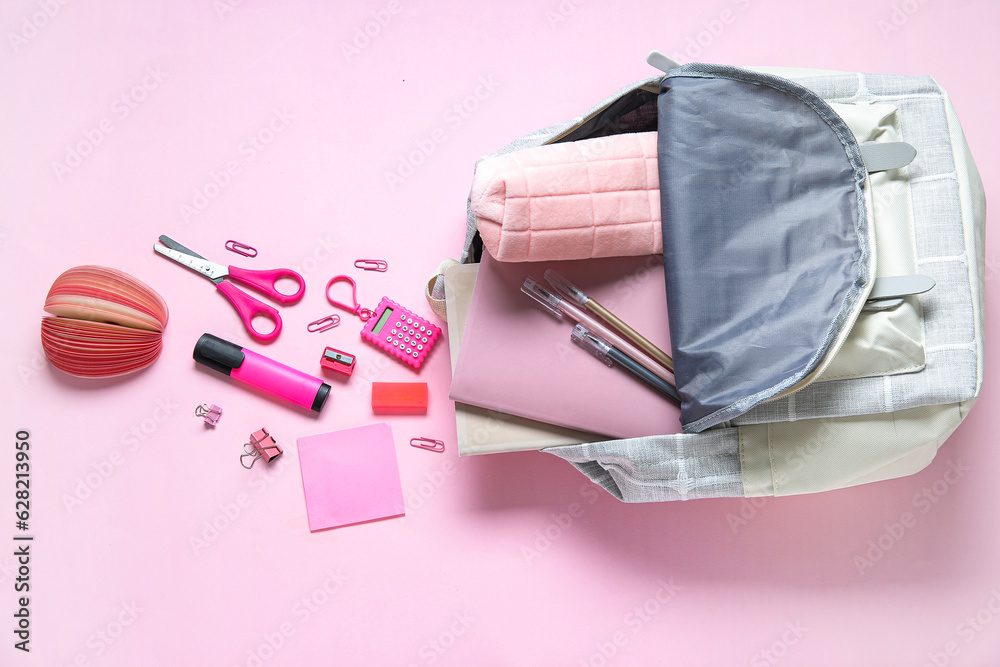 Color school backpack with different stationery on pink background