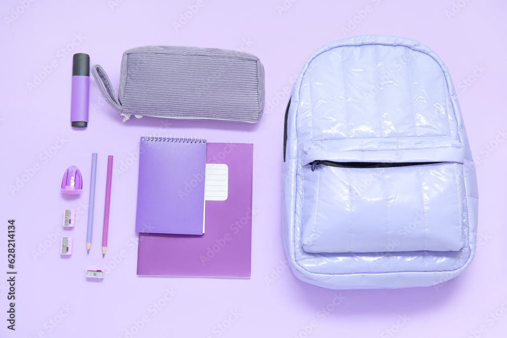 Lilac school backpack with different stationery on purple background