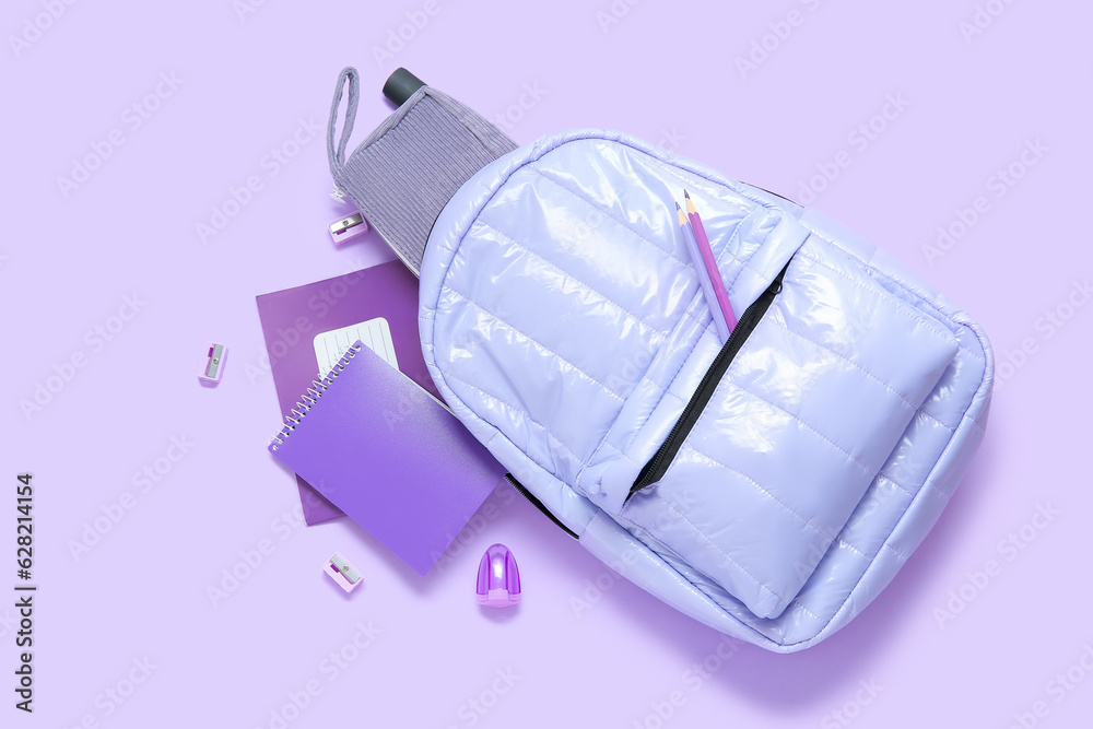 Lilac school backpack with different stationery on purple background