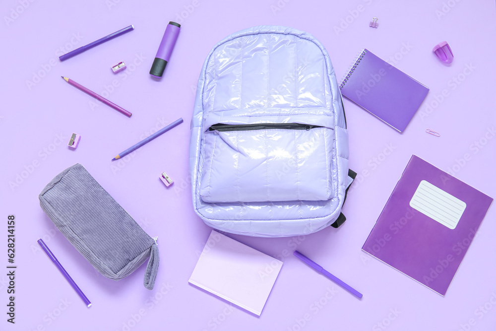 Lilac school backpack with different stationery on purple background