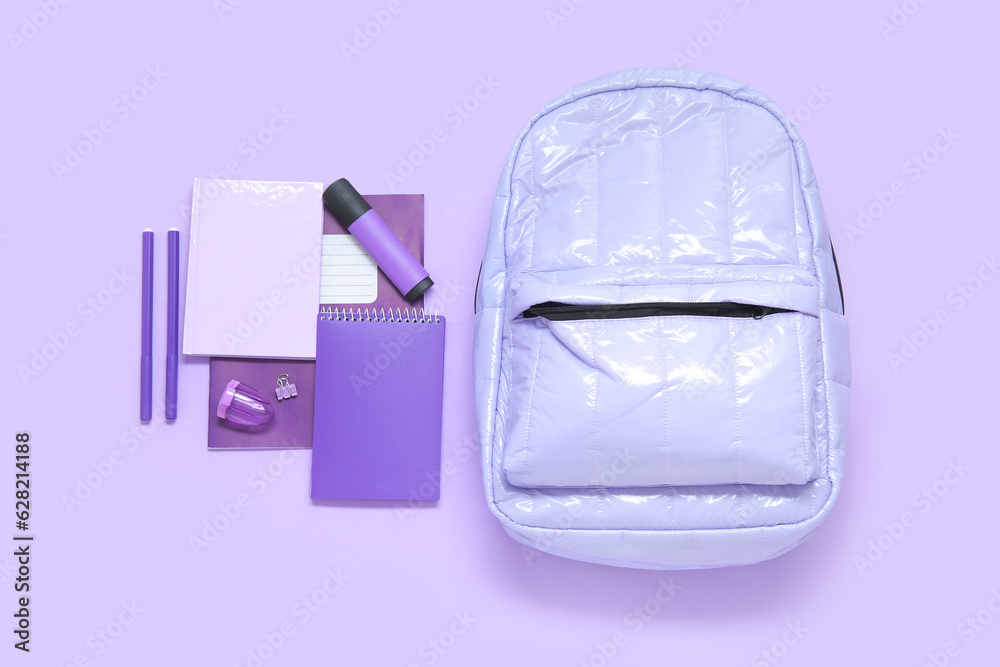 Lilac school backpack with different stationery on purple background