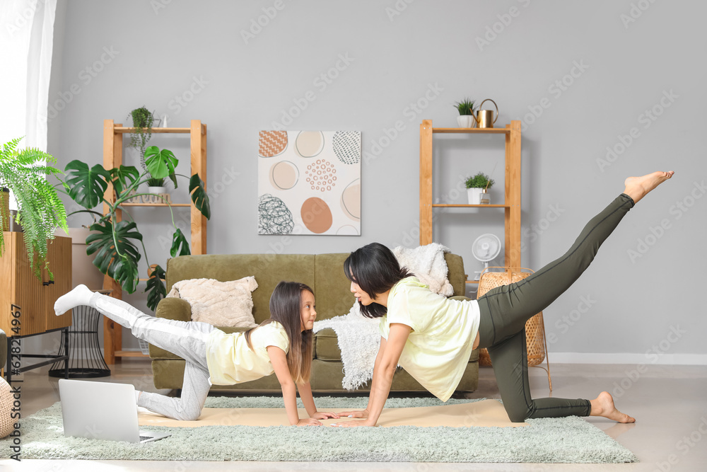 Asian mother with her little daughter training at home