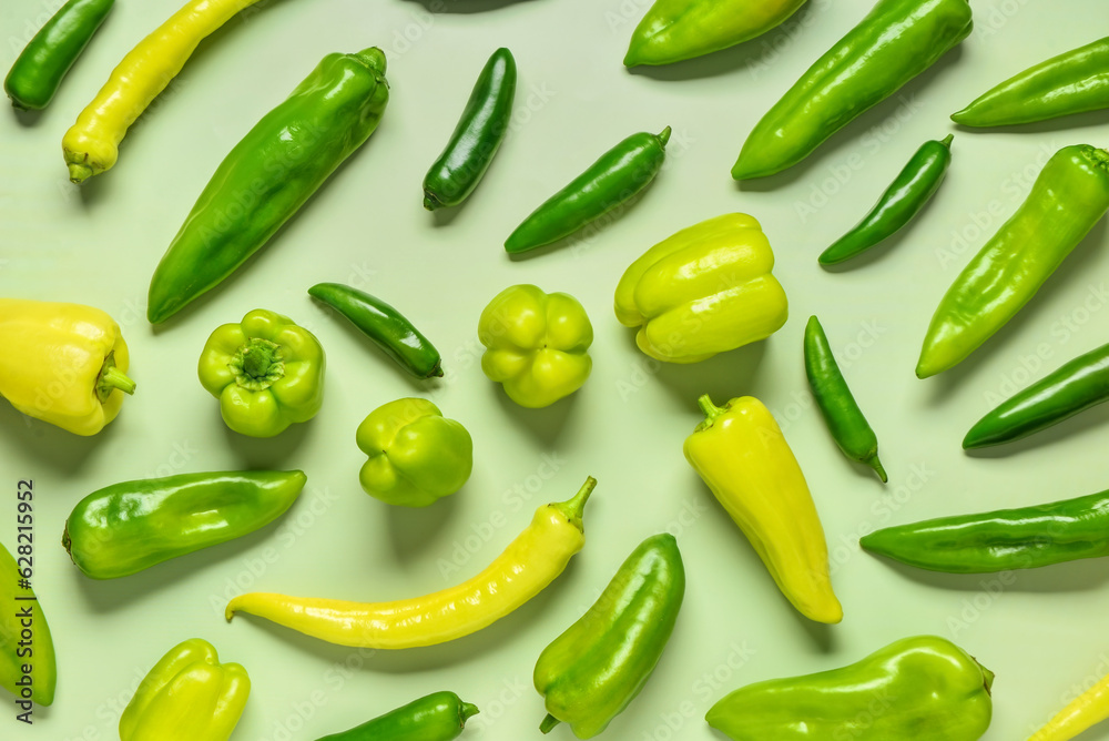 Different fresh peppers on green background