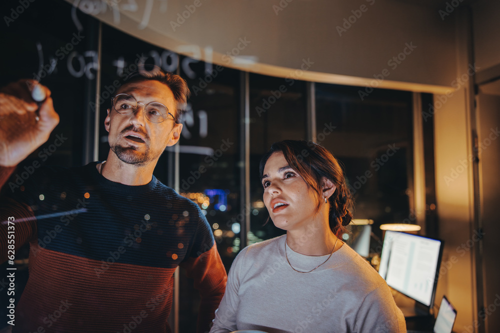 Business team having a late night brainstorming session in a glass walled office