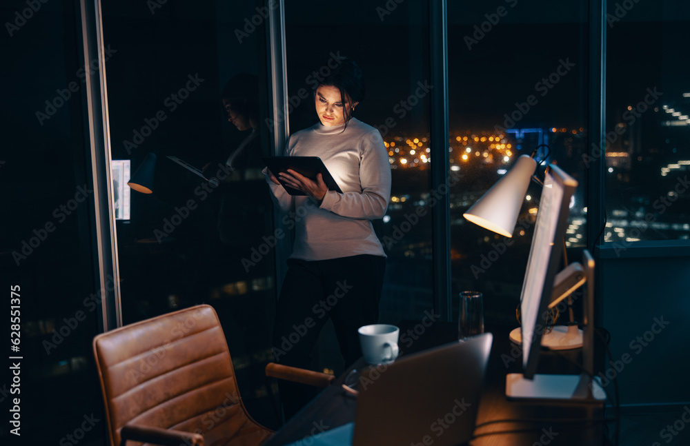 Female entrepreneur using a tablet in her office at night