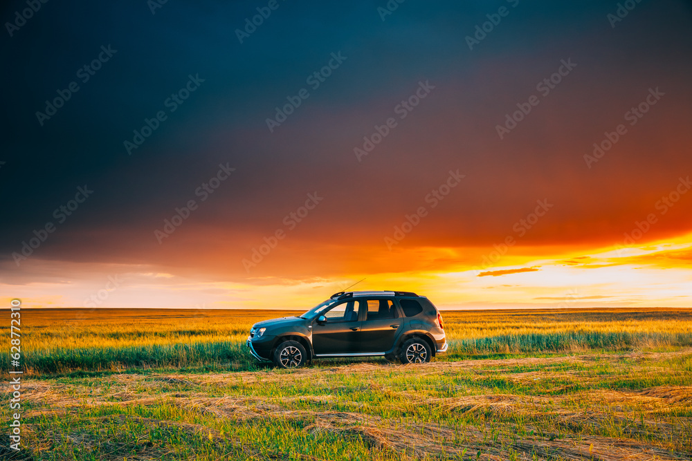 AWD 4WD SUV green car in summer meadow landscape in summer field countryside landscape. Sunset sky b