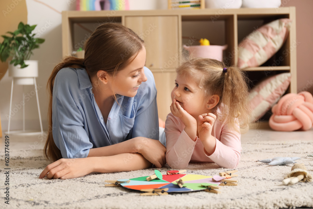 Cute little girl and her mother with matching game at home