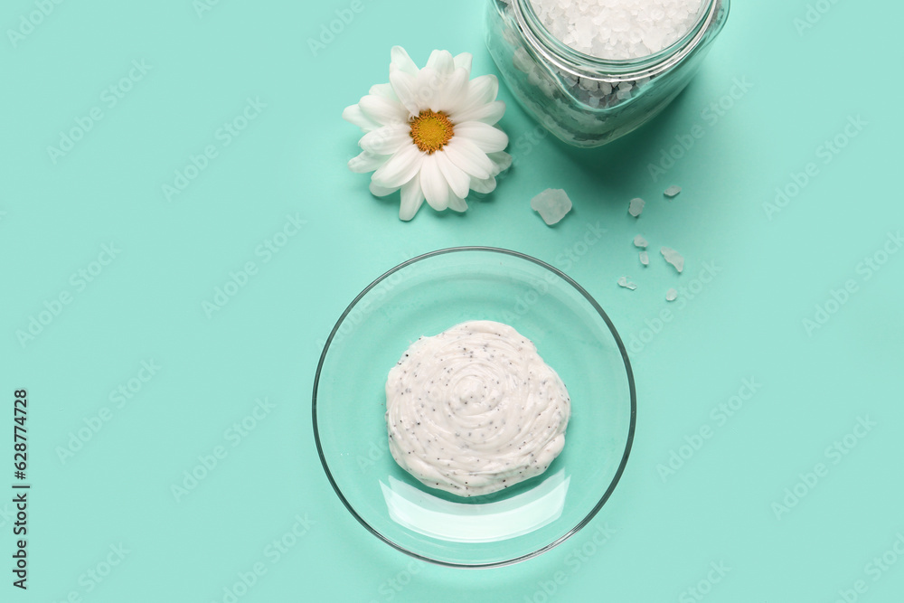 Bowl of body scrub, jar with sea salt and chamomile flower on color background