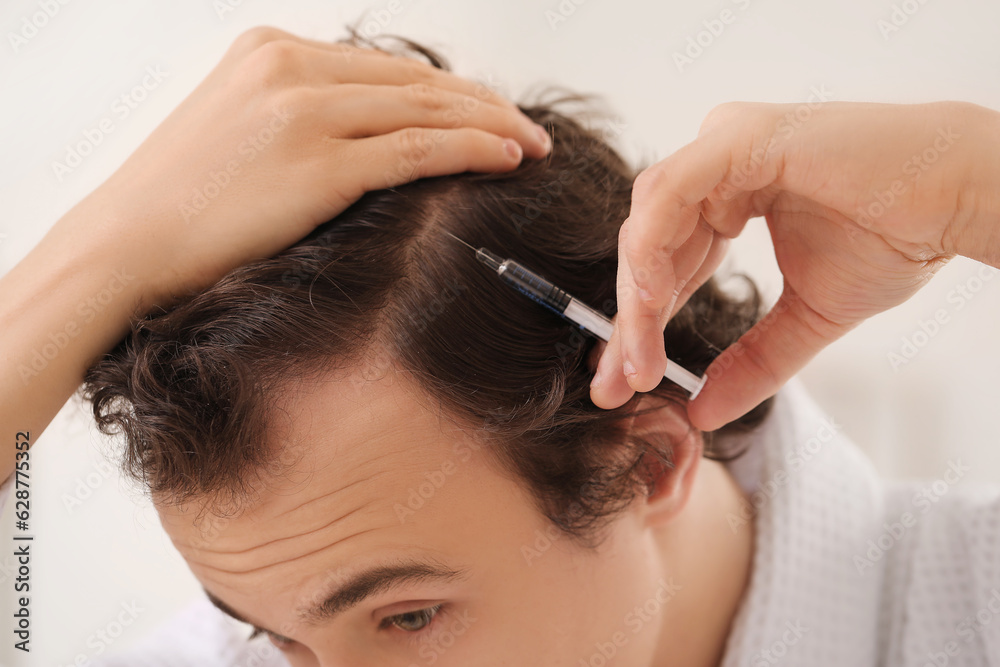 Young man with hair loss problem making injection in bathroom, closeup