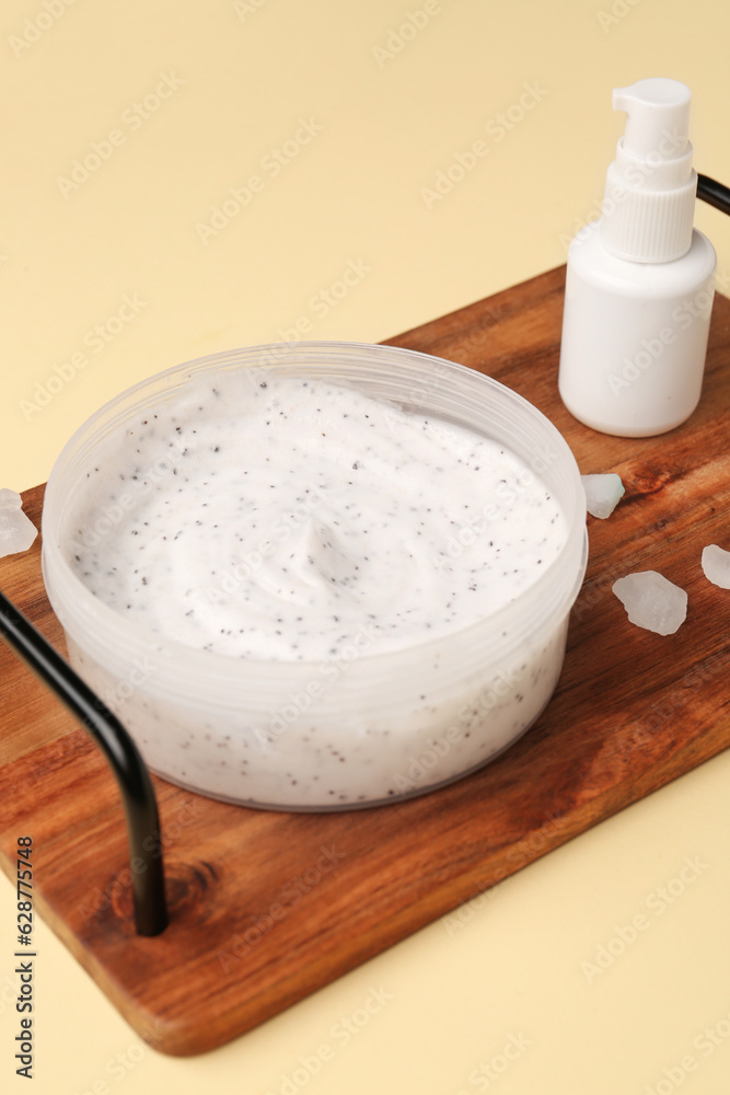 Wooden board with jar of body scrub and cosmetic product on color background, closeup