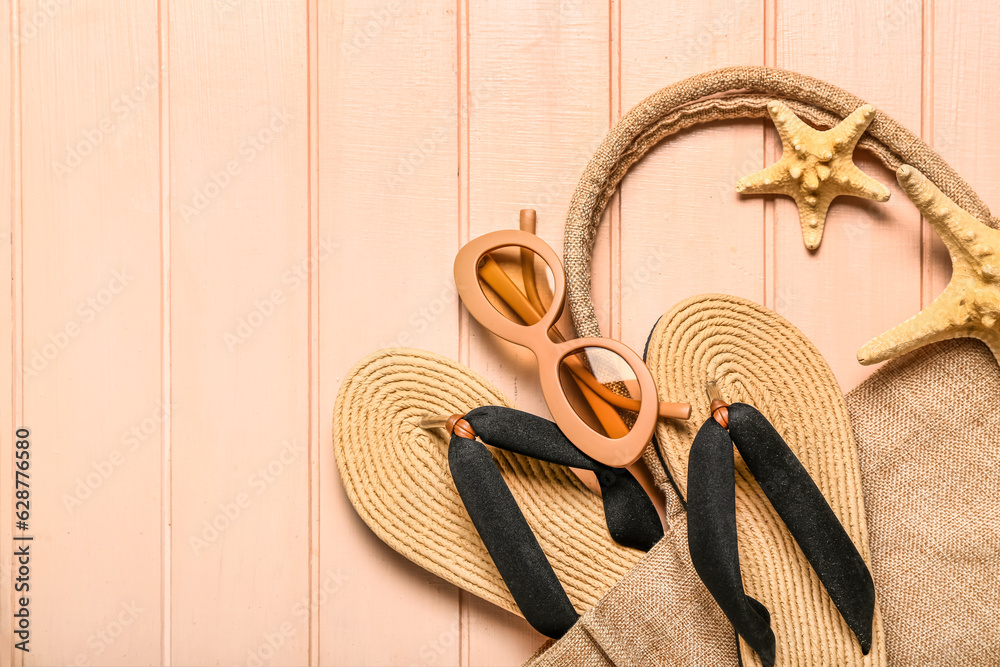 Flip-flops with sunglasses, starfishes and bag on beige wooden background