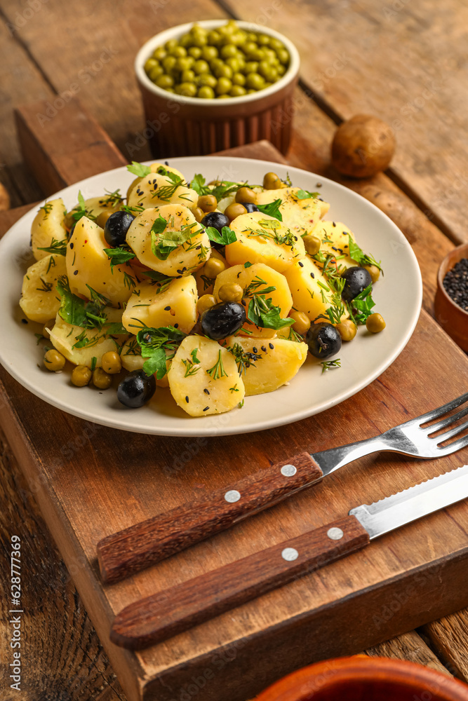 Plate of tasty Potato Salad with vegetables on wooden background