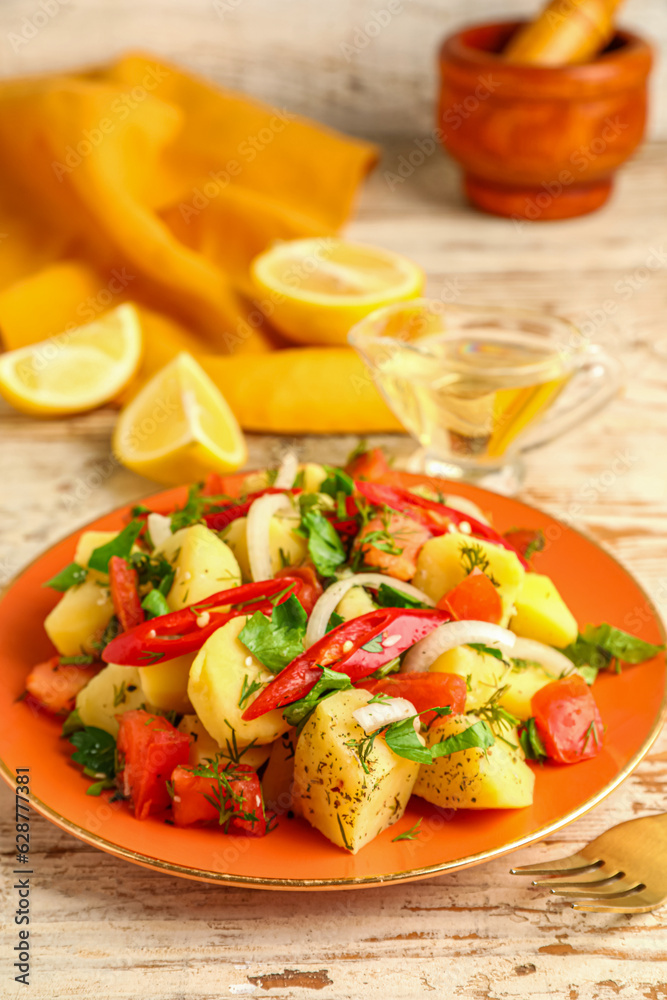 Plate of tasty Potato Salad with vegetables on light wooden background