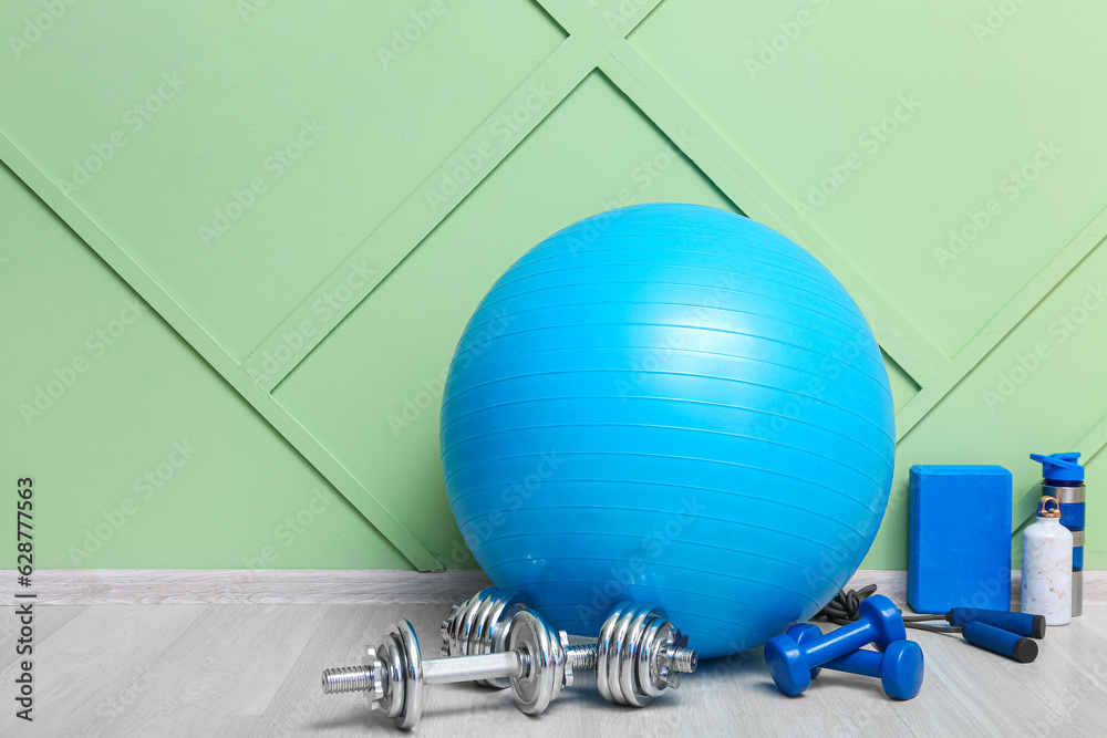 Sports equipment with dumbbells near green wall in gym