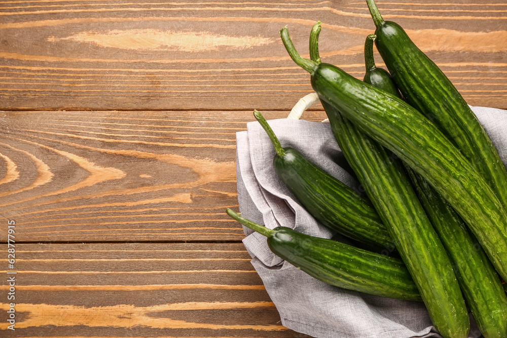 Basket with fresh cucumbers on wooden background, closeup