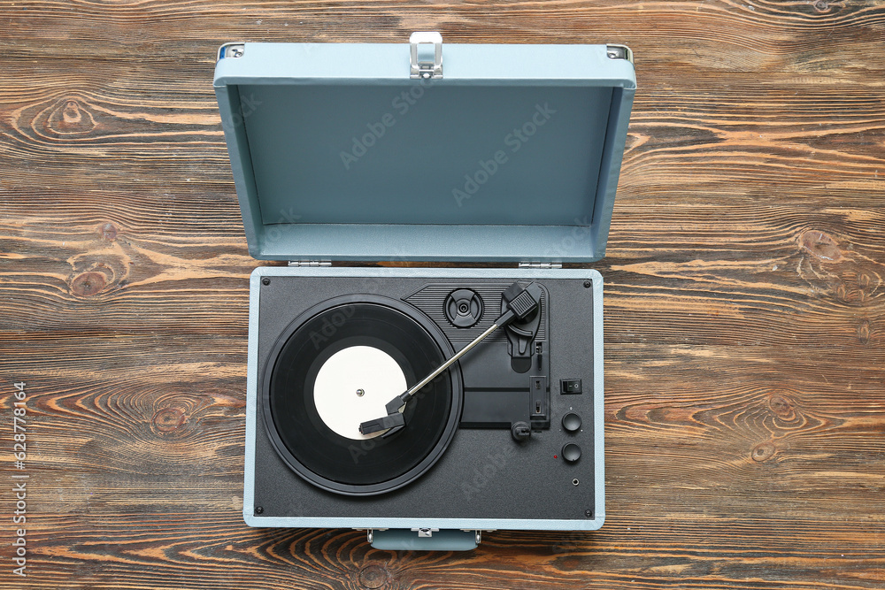 Record player with vinyl disk on wooden background