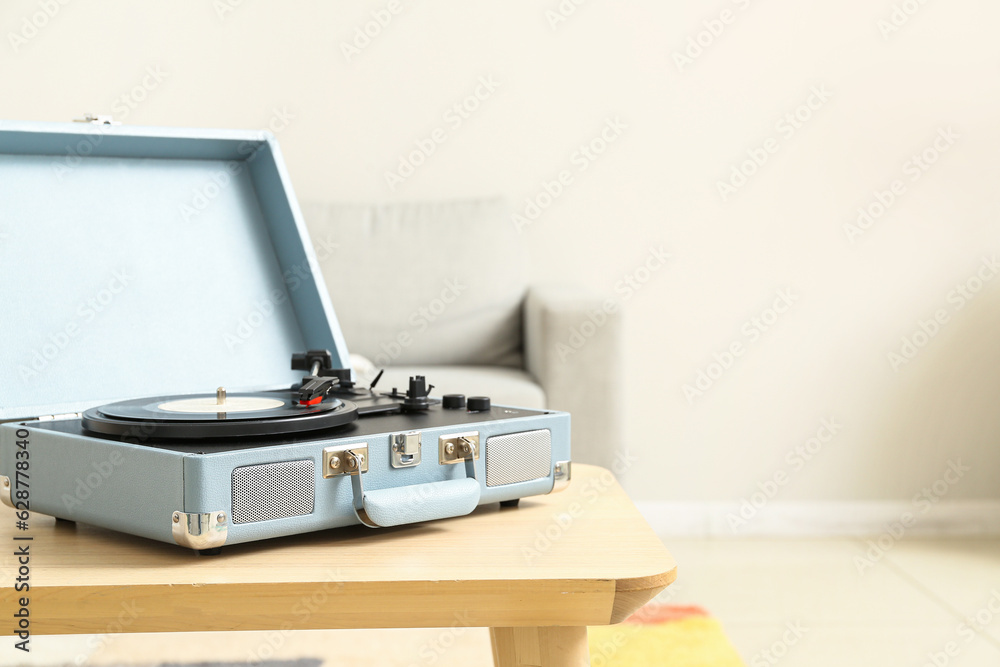 Record player with vinyl disk on table in room