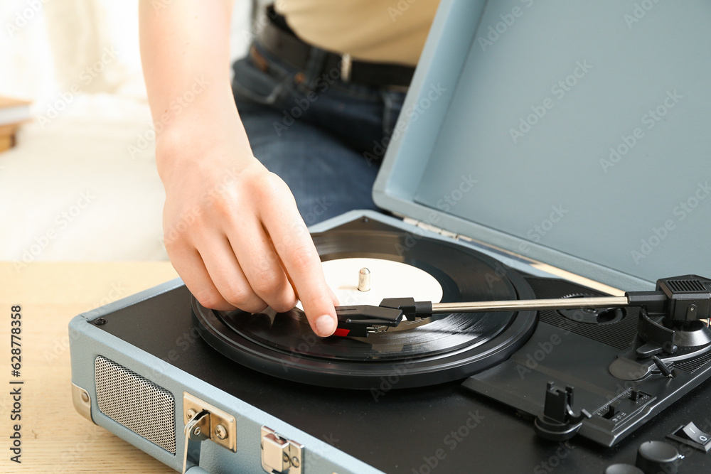 Woman using record player at home, closeup