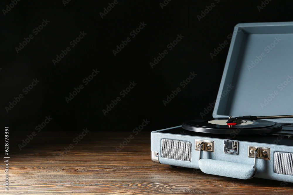 Record player with vinyl disk on dark wooden background