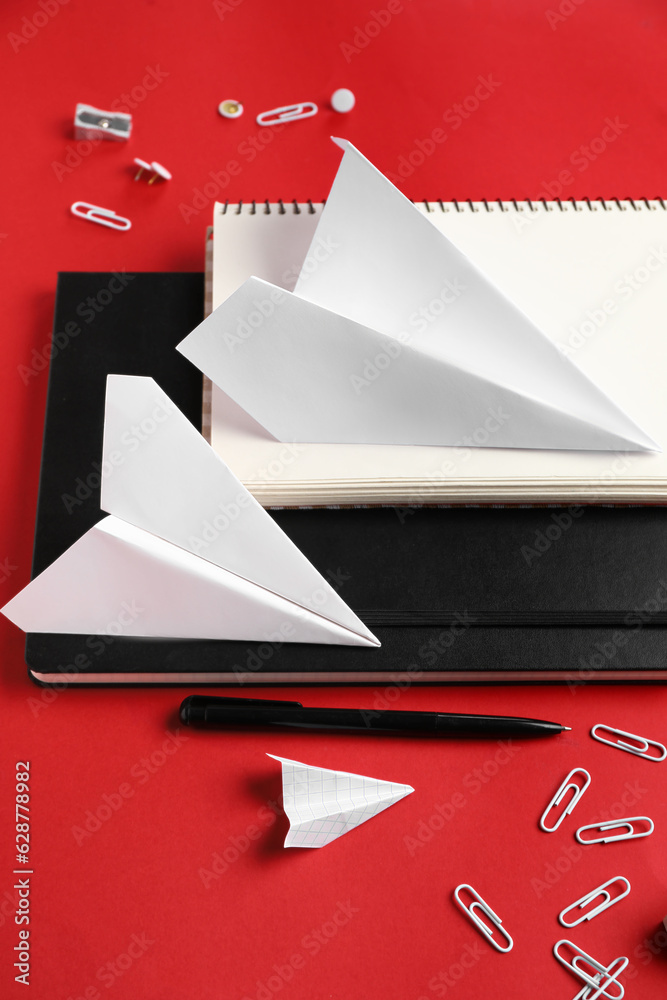 Composition with stationery supplies and paper planes on red background