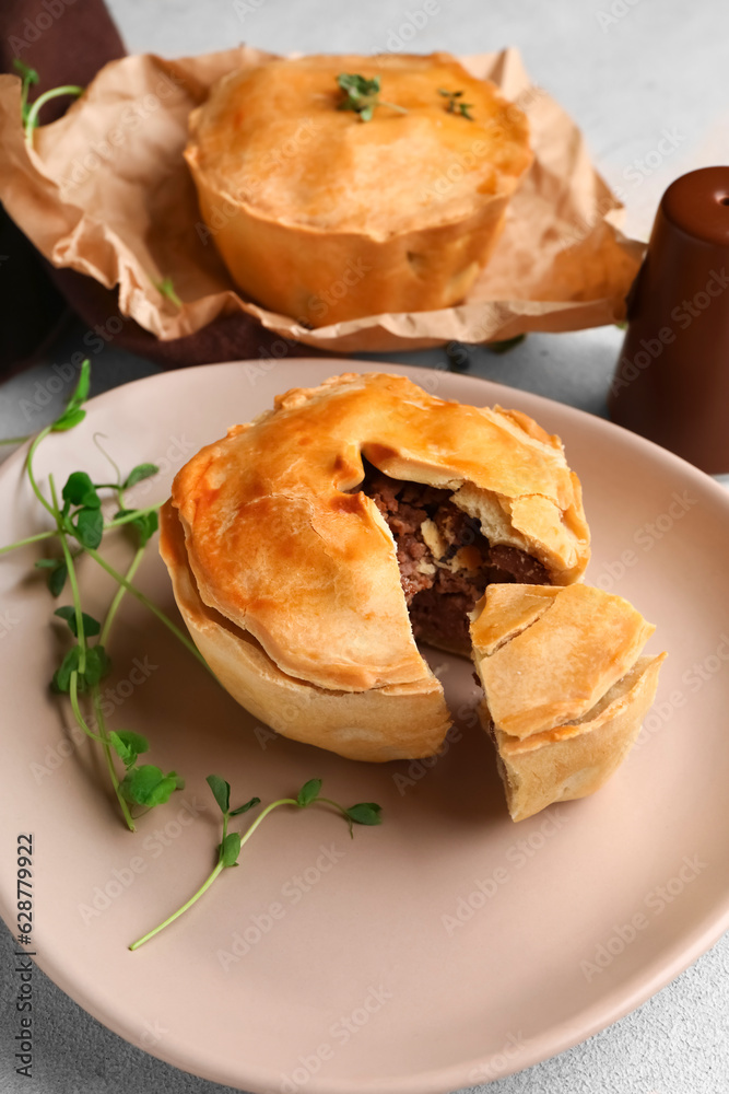 Plate with tasty meat pot pie on light background